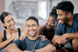 Group of diverse friends smiling and supporting each other in a gym setting, symbolizing the importance of men's health and well-being